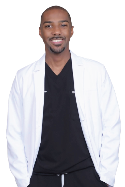 A man wearing a white coat and standing against a gray background.